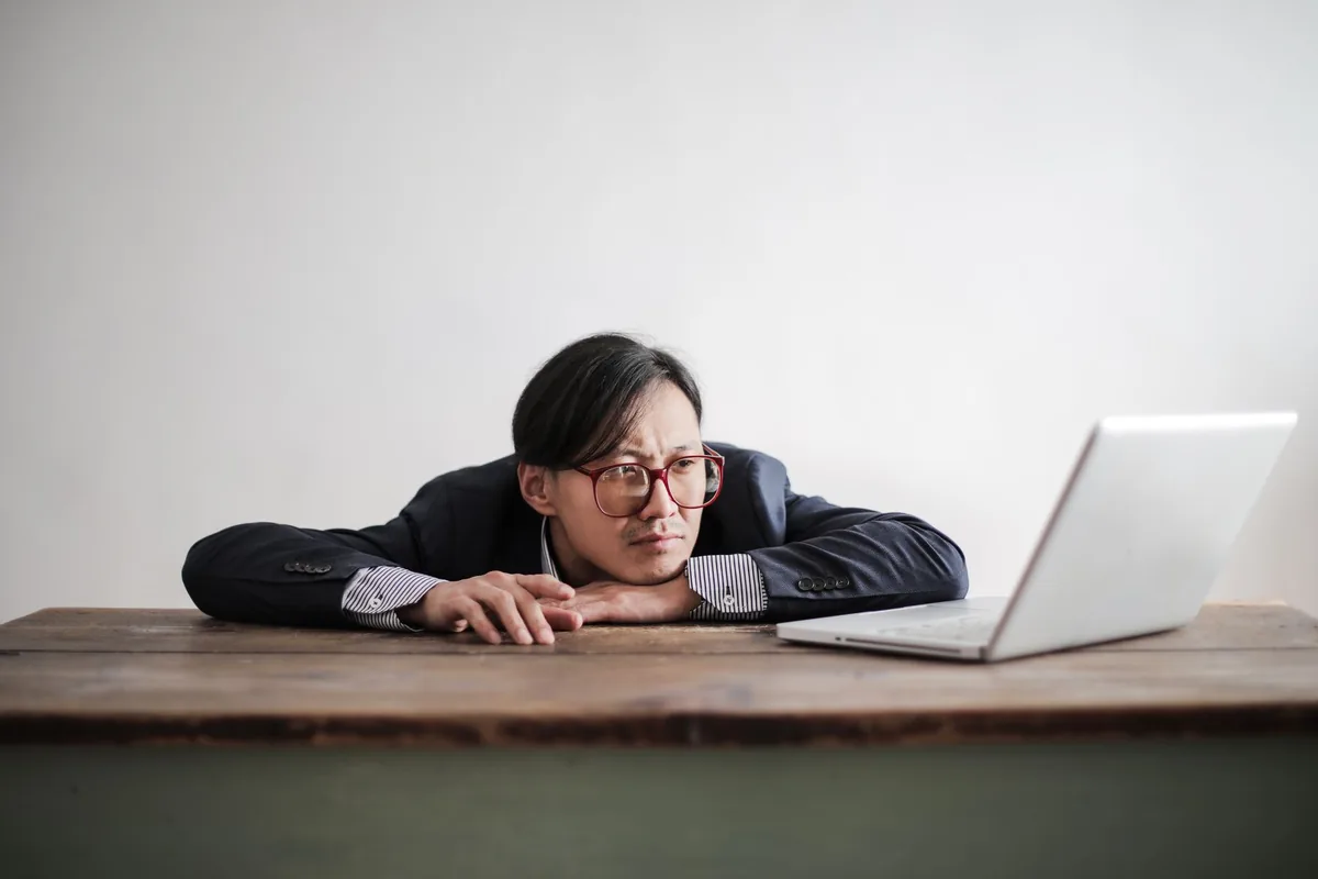A man looking bored and disengaged at his desk.