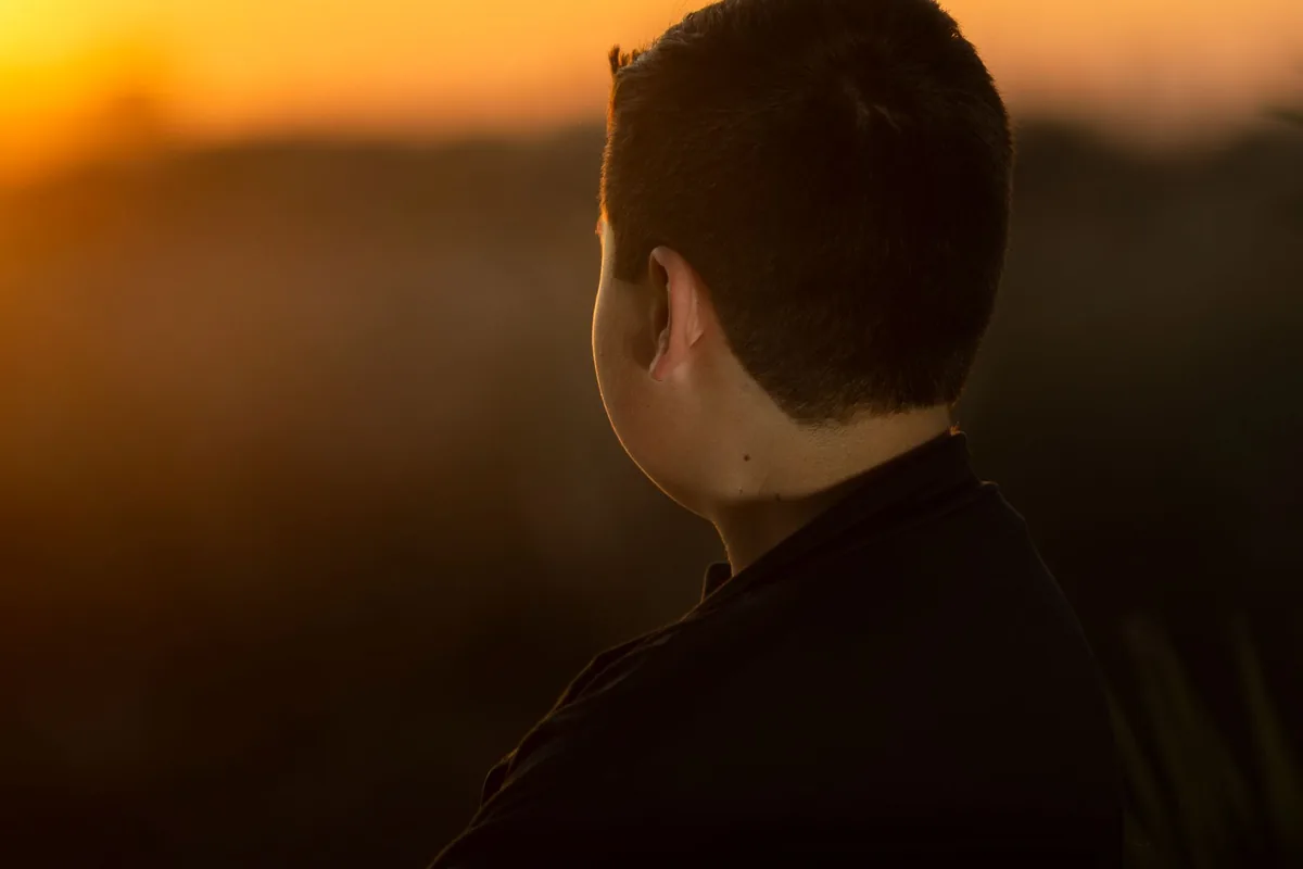 A person watching a sunrise, looking toward the horizon.