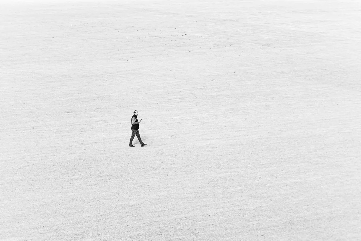 A solitary figure walking across a vast, empty landscape.